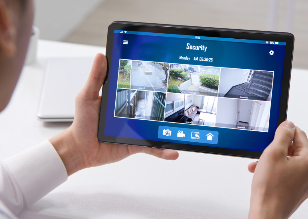 a man is holding a tablet displaying different security camera images - One of 5 Ways That Advanced Security Can Protect Your Business Assets